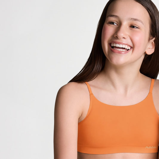 girl wearing an orange sports bralette against a plain background