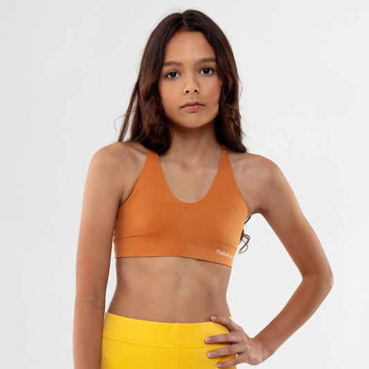 Tween Girl wearing a caramel vneck sports bra and yellow leggings on a white background