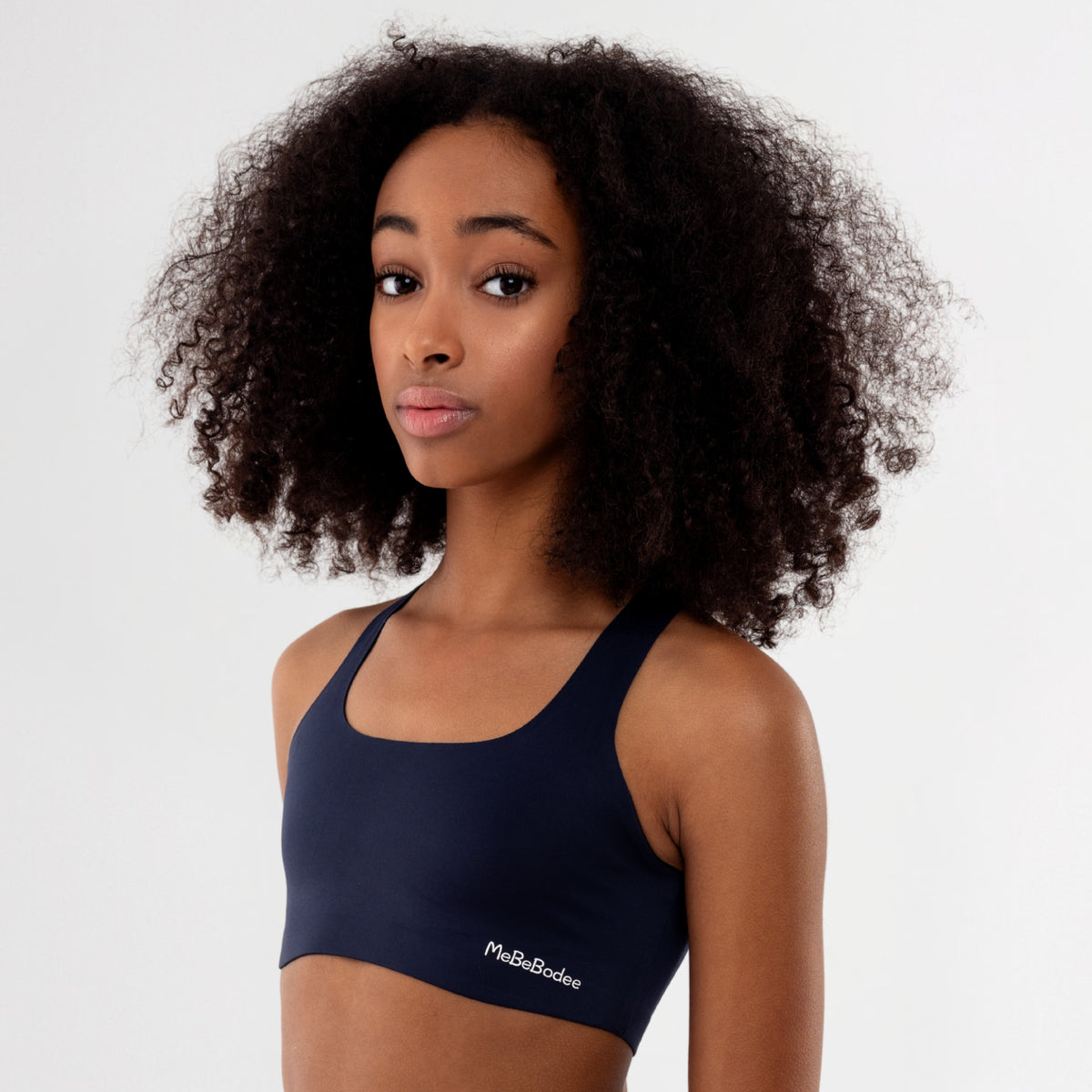 Teen Girl wearing a navy blue sports bra with 'MeBeBodee' branding on a white background