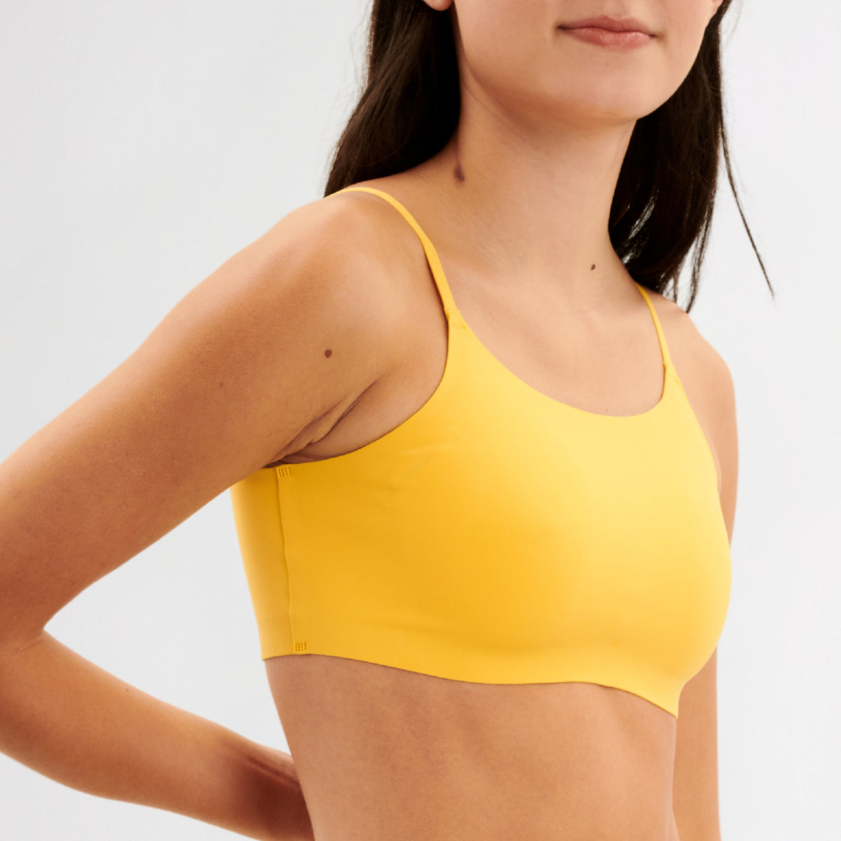 Yellow sports bralette worn by a teen girl on a light gray background