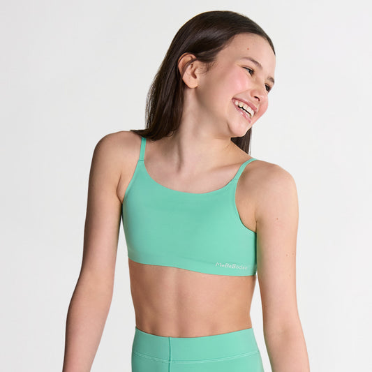 Tween Girl wearing a green sports bralette and leggings on a light gray background