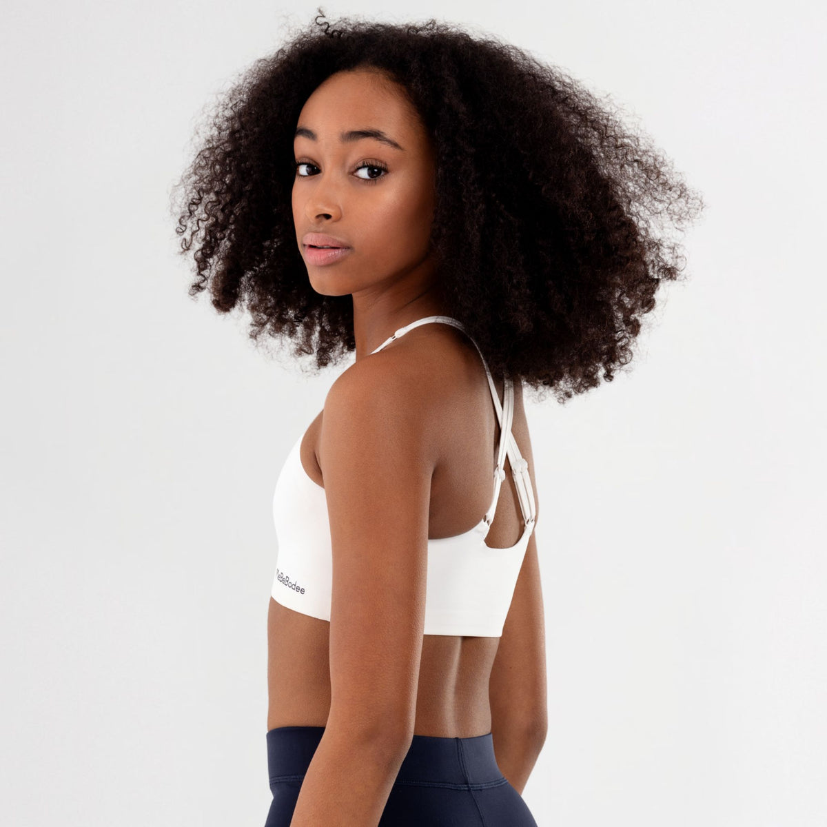 Tween Girl wearing a white sports bra with a MeBeBodee brand logo on a light grey background